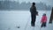 Father and daughter are near the stables in winter