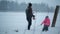 Father and daughter are near the stables in winter