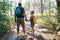 Father with daughter on path in pine tree forest