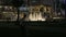 The father and daughter play against the background of the night city with a beautiful view of the fountain.