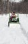 Father and daughter plow a snowy drive on a tractor