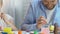 Father and daughter preparing for Easter, drawing eggs with colorful paints