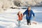 Father And Daughter Pulling Sledge Up Snowy Hill