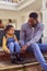 Father And Daughter Sit On Step At Home Putting On Boots Before Going On Family Walk 