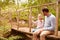 Father with daughter sitting at wooden bridge