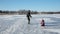 Father and daughter sledding on frozen lake