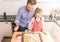 Father and daughter sprinkling powdered sugar on cookies