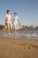 Father and Daughter walking along the waters edge, beach, China