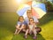 Father and daughters sitting on a meadow with colorful umbrella