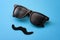 Father day and male hipster fashion concept with minimalist image of a pair of square sunglasses and a fake moustache on colorful