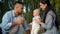 Father drinking juice and playing with baby at picnic