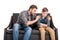 Father embracing and talking with upset little son sitting on sofa with crossed arms