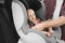 Father fastening baby to child safety seat inside