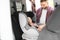 Father fastening baby to child safety seat inside