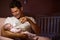 Father Feeding Baby With Bottle In Nursery