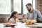 Father feeding grumpy daughter with porridge during breakfast