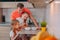 A father feeds his daughters in the kitchen on a background of fruits