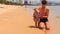 father feeds little girl sitting on edge of seawater on beach