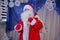 Father Frost speaks with a microphone . Santa Claus is singing Christmas songs against . Man in Santa Claus suit posing with