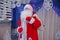 Father Frost speaks with a microphone . Santa Claus is singing Christmas songs against . Man in Santa Claus suit posing with