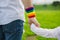 Father with gay pride rainbow flag wristband and his son walking in the park. Paternal concept