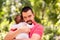 Father gently holding in arms infant daughter in pink jumpers outdoors in warm sunny or early autumn day. Baby is hugging dad