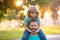 Father giving son ride on back in park. Portrait of happy father giving son piggyback ride on shoulders. Cute child with