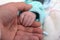 a father hand and his newborn hand together, family care concept, a neonate infant small hand holds his dad hand feeling security