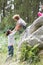 Father Helping Children To Jump Off Rocks