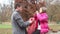 Father helping daughter put on jacket and scarf in the park