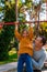 Father helping daughter to pull up on the uneven bars at the playground. Healthy family concept