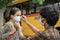 Father helping daughter to wear mask before getting inside the school bus as coronavirus or covid-19 safety measures - concept of