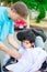 Father helping disabled son in wheelchair drink from straw cup