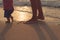 Father helping his baby with the first steps, teaching baby to walk concept, outdoor candid photo on the beach, spending