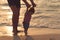 Father helping his baby with the first steps, teaching baby to walk concept, outdoor candid photo on the beach, spending