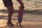 Father helping his baby with the first steps, teaching baby to walk concept, outdoor candid photo on the beach, spending