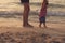 Father helping his baby with the first steps, teaching baby to walk concept, outdoor candid photo on the beach, spending