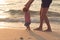 Father helping his baby with the first steps, teaching baby to walk concept, outdoor candid photo on the beach, spending