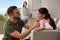 Father helping his daughter to get ready for school while mother gathering books indoors