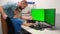 Father helping or teaching the child to type on the keyboard agains two green screens or monitors. remote learning at