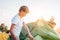 Father helps his son setting tent on sunset forest glade