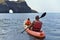 A father and his little daughter are sailing on the sea in a kayak to a grotto