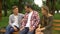 Father and his male and female teenage children talking on bench in park, relax