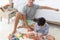 Father and his mixed-race son playing colorful wooden block together with joy and happiness in home bed room. Idea for learning