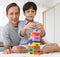 Father and his mixed-race son playing colorful wooden block together with joy and happiness in home bed room. Idea for learning