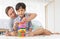 Father and his mixed-race son playing colorful wooden block together with joy and happiness in home bed room. Idea for learning