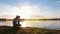 Father and his son angling on the riverside at sunset