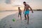 Father with his son plaing football on the beach.