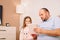 Father holding a paper and a pen and tries to explain to his daugher what is written, she watching and smiling.