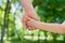 Father holds the hand of a little child in sunny park outdoor, united family concept